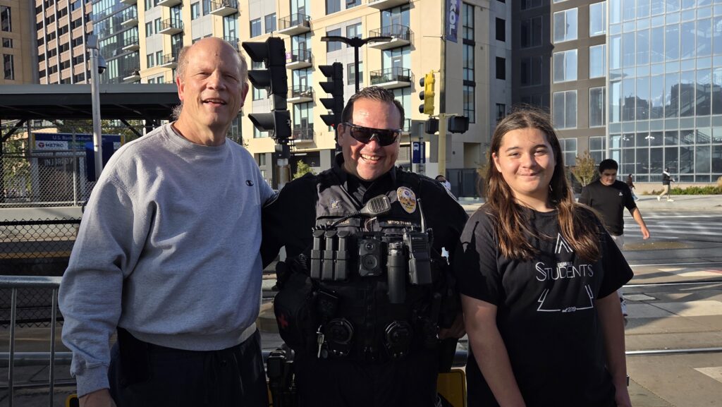Zeke and I posed with a police officer after the Minneapolis No Kings rally on October 18, 2025 near the light rail train station. People who spew lies about how this was a hate America rally should be ashamed.